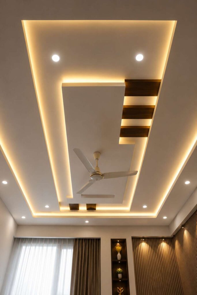 Modern geometric false ceiling design with layered POP panels, warm LED cove lighting, wooden accent strips, recessed spotlights, ceiling fan, and contemporary bedroom interior decor.