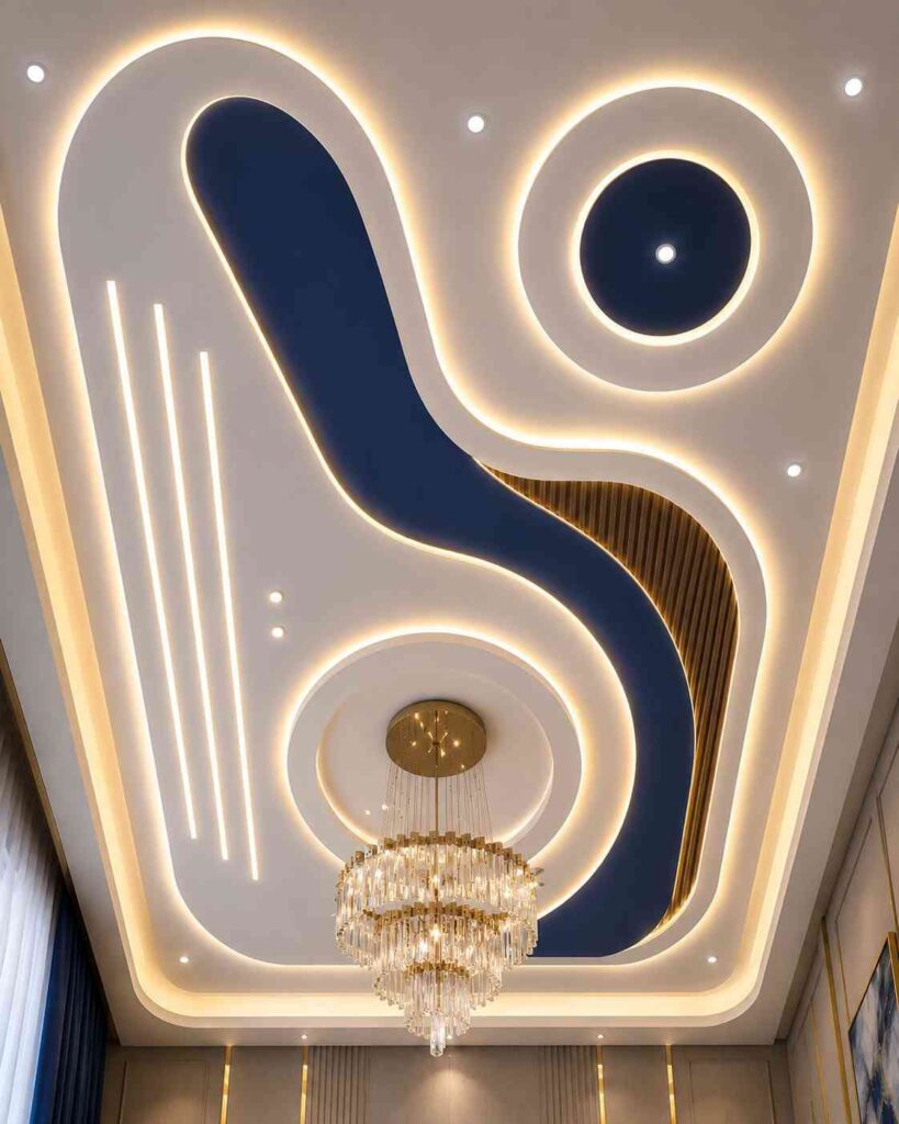 Abstract POP false ceiling with curved gypsum design, recessed LED cove lighting, crystal chandelier, decorative ceiling panels, and luxury interior ceiling detailing for a living room.